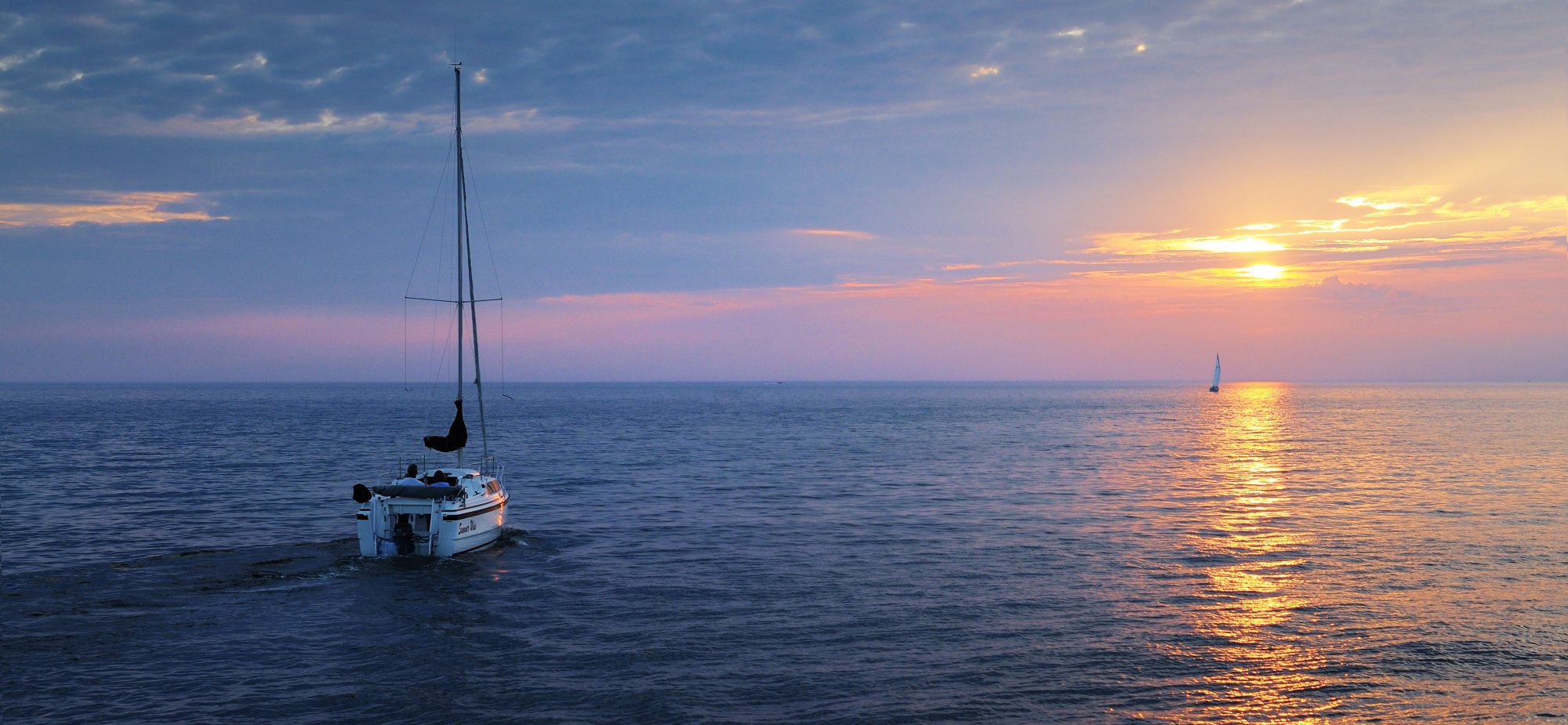 A boat on calm waters overlooking a gorgeous sunset